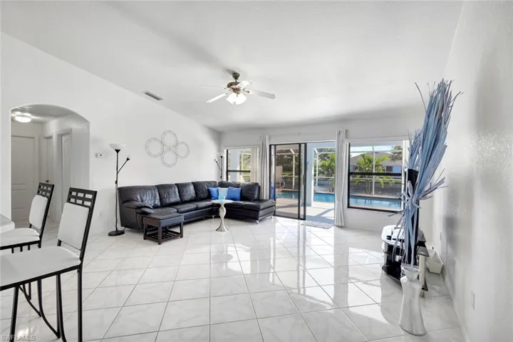 Living area with arched walkways, a ceiling fan, and light tile patterned flooring
