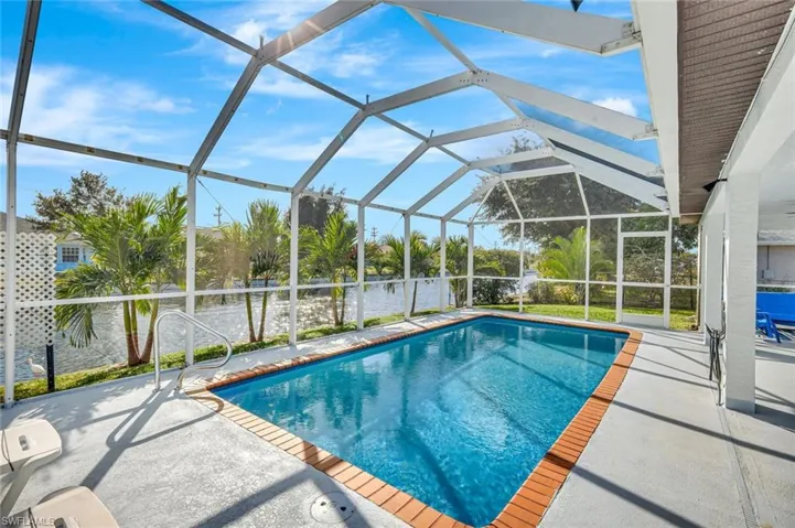 Swimming pool featuring a lanai, a sunroom, and a patio area