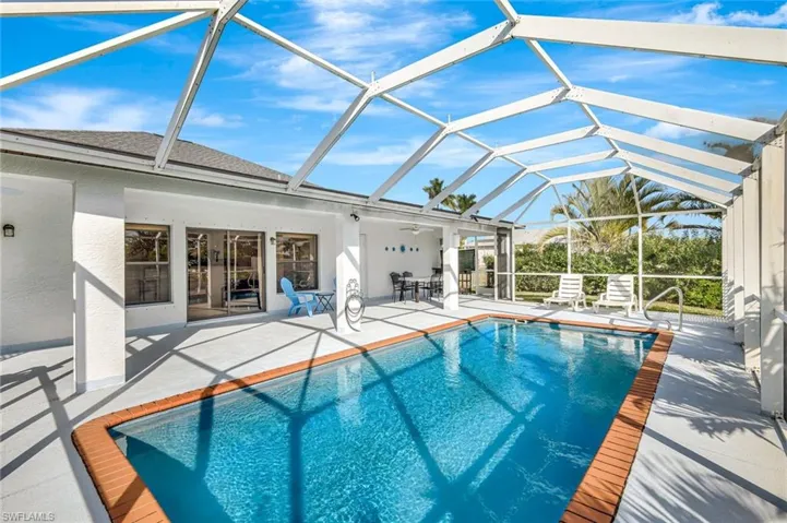 Outdoor pool with a sunroom, glass enclosure, and a patio area