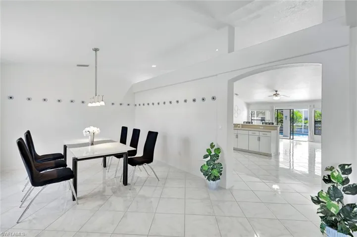 Dining space with arched walkways, a ceiling fan, and light tile patterned floors