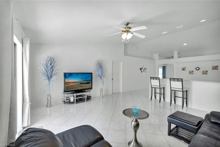 Living area with ceiling fan, vaulted ceiling, and light tile patterned flooring