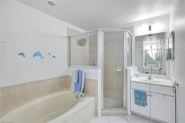 Full bath featuring a garden tub, vanity, a shower stall, and light tile patterned flooring