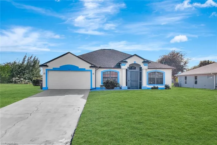 View of front facade featuring driveway, stucco siding, a front lawn, and a garage