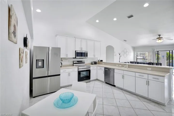 Kitchen featuring stainless steel appliances, white cabinets, arched walkways, a peninsula, and recessed lighting