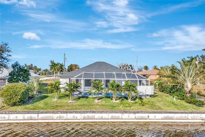 Back of property with glass enclosure, a water view, a yard, and a sunroom