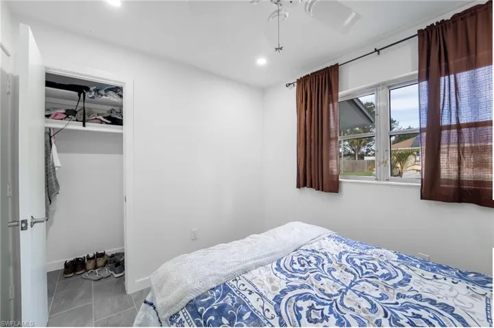 Bedroom with ceiling fan, light tile patterned flooring, and a closet