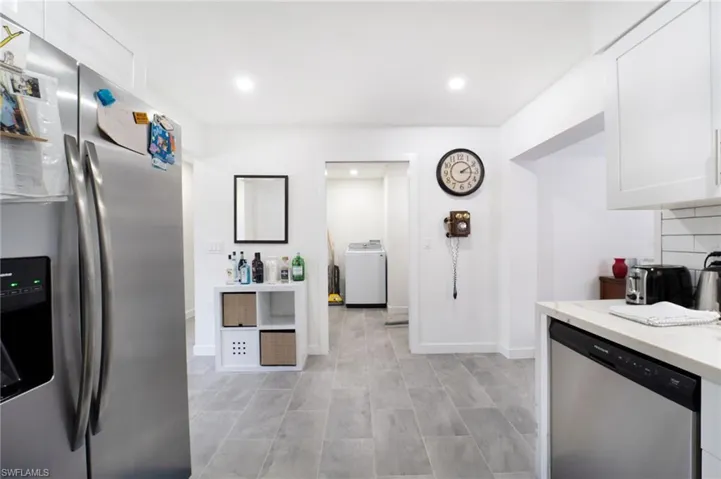 Kitchen with appliances with stainless steel finishes, washer / clothes dryer, and white cabinetry