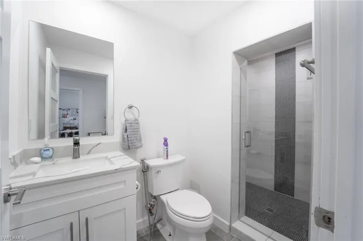 Bathroom with an enclosed shower, vanity, toilet, and tile patterned floors
