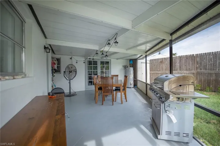 Sunroom / solarium with lofted ceiling with beams, gas water heater, and french doors