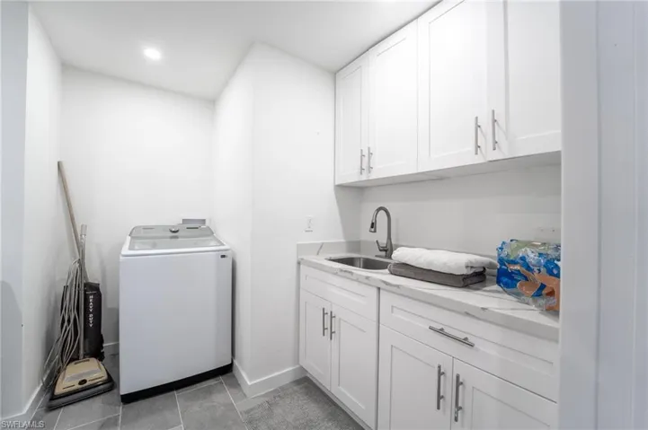 Laundry room with cabinets, light tile patterned floors, washer / clothes dryer, and sink
