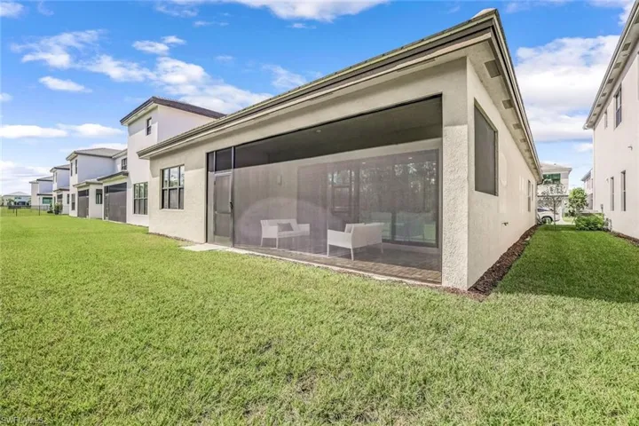 Back of property featuring a lawn and a screened lanai