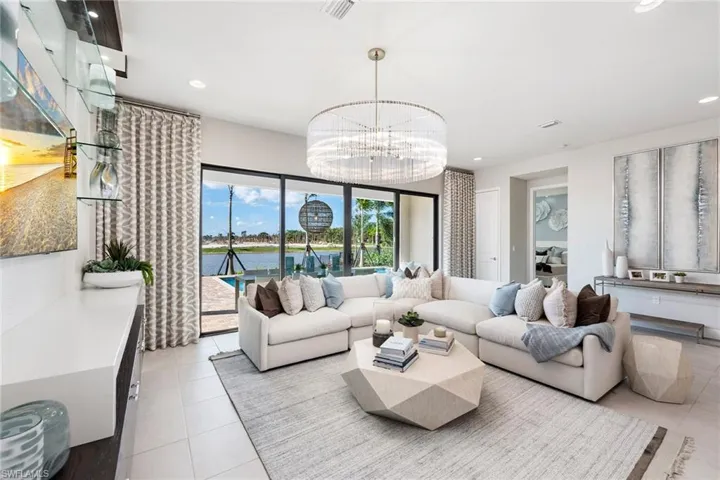 Living room with light tile patterned flooring, a notable chandelier, and a water view