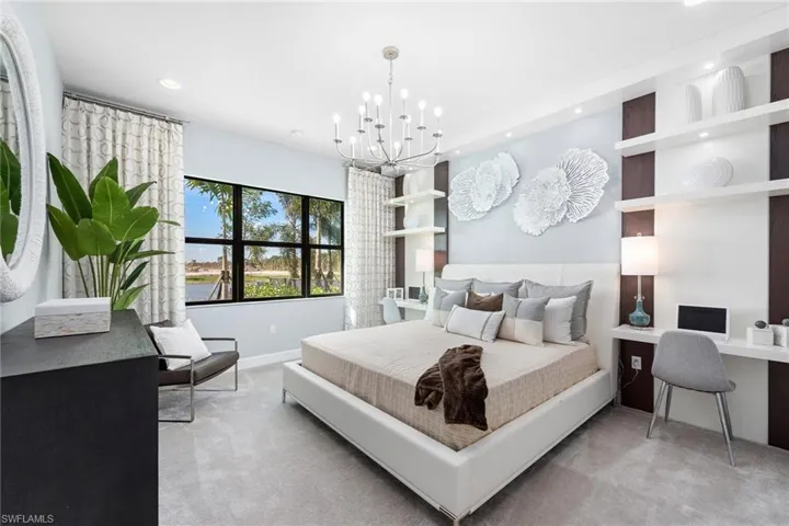 Bedroom featuring an inviting chandelier, light colored carpet, and built in desk