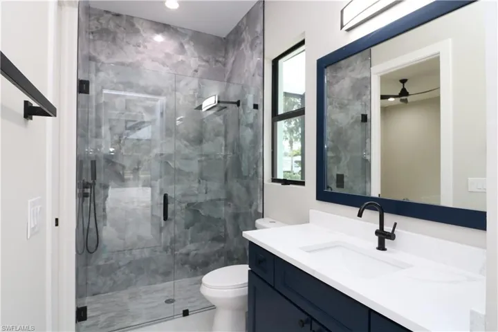 Bathroom featuring vanity, a shower with shower door, and toilet