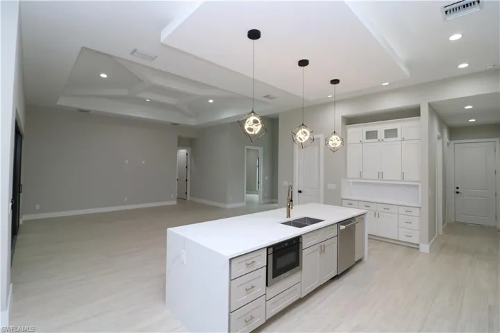 Kitchen with hanging light fixtures, sink, white cabinets, an island with sink, and stainless steel appliances