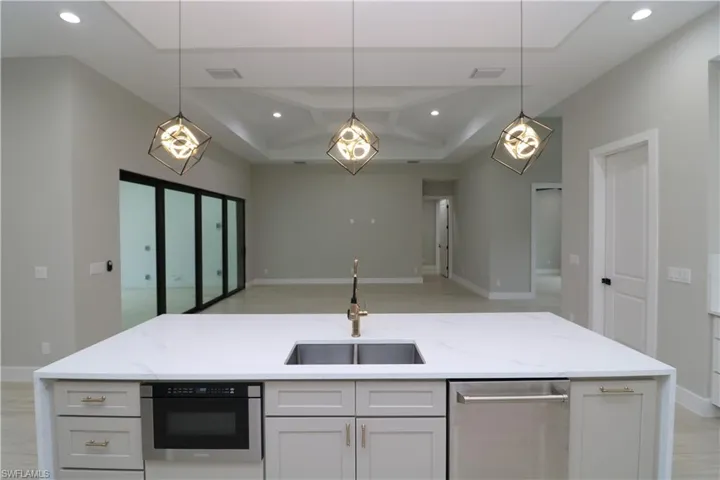 Kitchen with sink, decorative light fixtures, and white cabinetry
