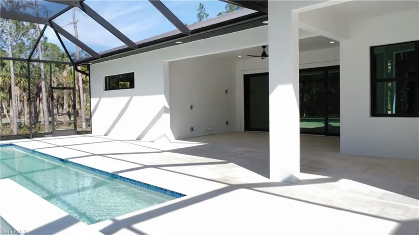 View of swimming pool featuring a lanai, a patio area, and ceiling fan