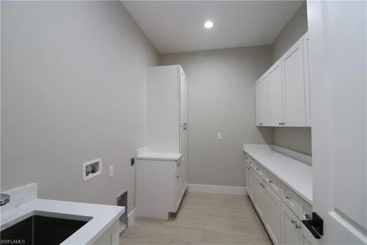 Washroom featuring cabinets, sink, hookup for a washing machine, light wood-type flooring, and hookup for an electric dryer