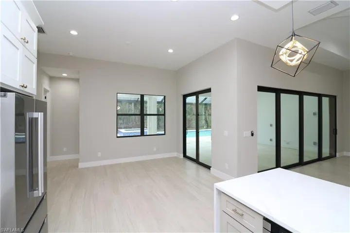 Kitchen featuring hanging light fixtures, white cabinets, light hardwood / wood-style flooring, and high end fridge
