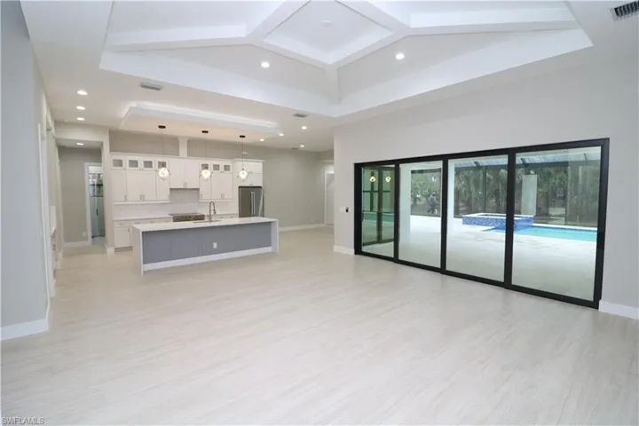 Unfurnished living room featuring sink, light hardwood / wood-style flooring, and a tray ceiling