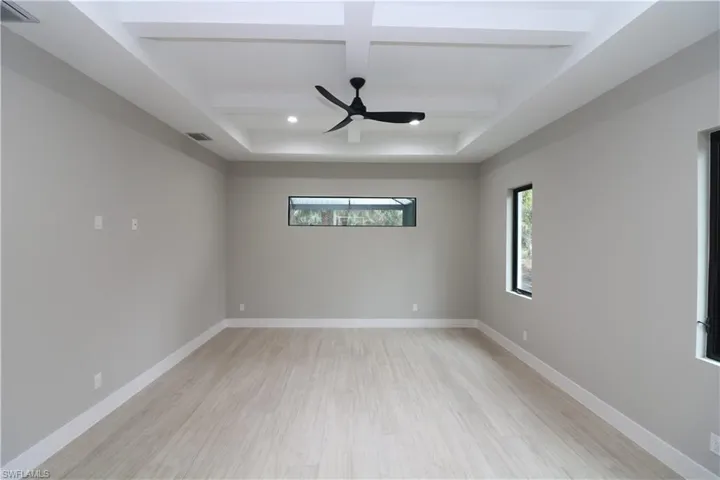 Unfurnished room featuring coffered ceiling, beamed ceiling, ceiling fan, and light hardwood / wood-style floors