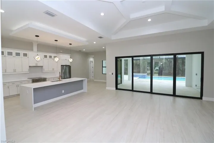 Kitchen featuring pendant lighting, sink, white cabinetry, a center island with sink, and stainless steel appliances