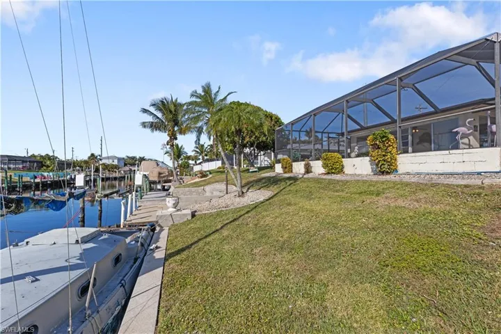 View of dock featuring a water view, a yard, and a lanai