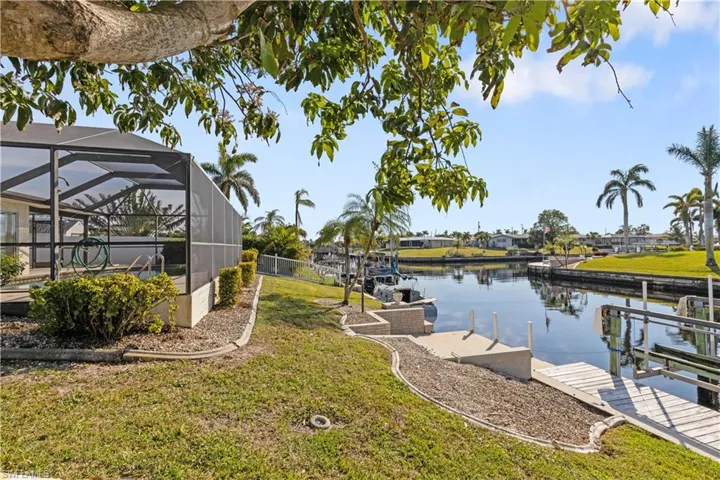 View of dock featuring a yard, a lanai, and a water view