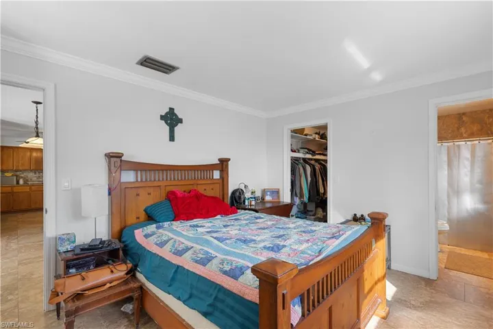Bedroom featuring a walk in closet, ornamental molding, connected bathroom, and a closet