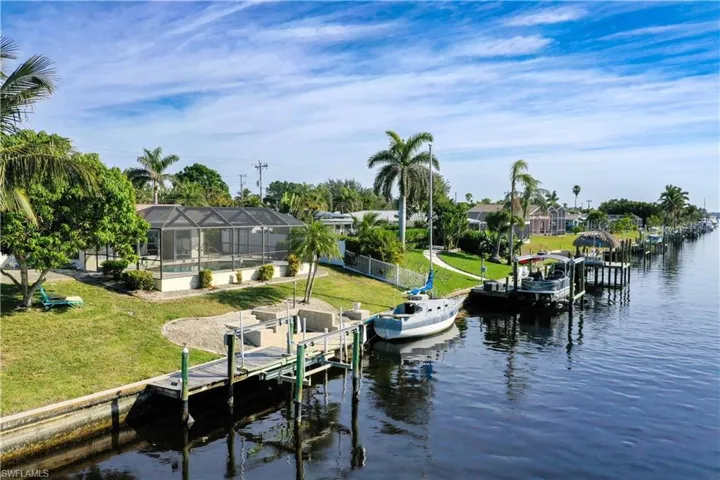 View of dock featuring a water view, a yard, and a lanai
