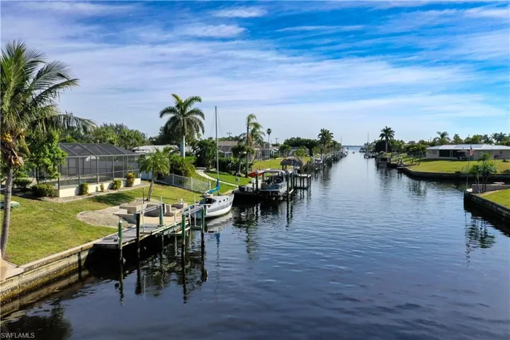 Dock area featuring a water view, glass enclosure, and a lawn