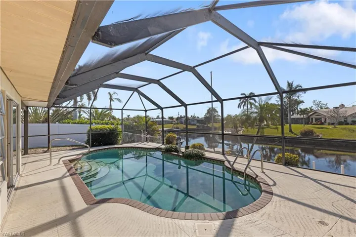 View of swimming pool featuring a water view, glass enclosure, and a patio area