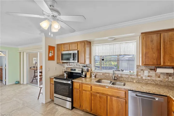 Kitchen featuring tasteful backsplash, sink, crown molding, and stainless steel appliances