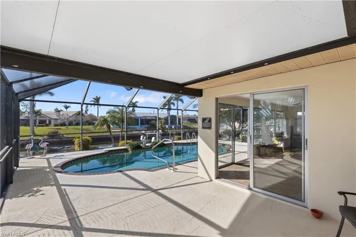 View of pool with glass enclosure and a patio