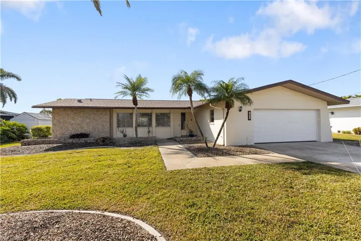 Ranch-style house featuring a garage and a front lawn