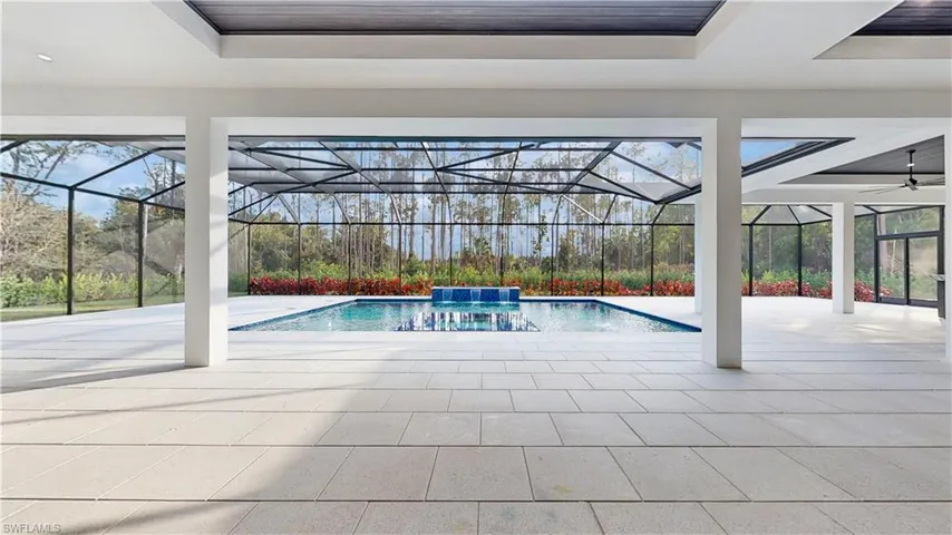 View of pool with pool water feature, a patio area, and glass enclosure