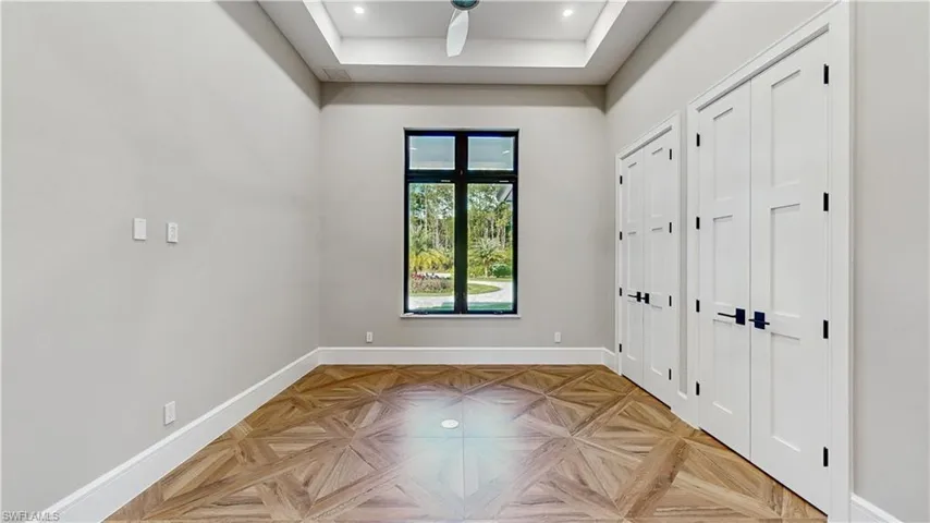 Unfurnished bedroom with light parquet flooring and a tray ceiling