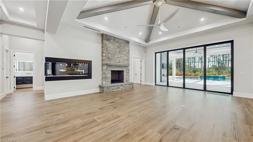 Unfurnished living room with ceiling fan, light hardwood / wood-style flooring, a fireplace, and a high ceiling