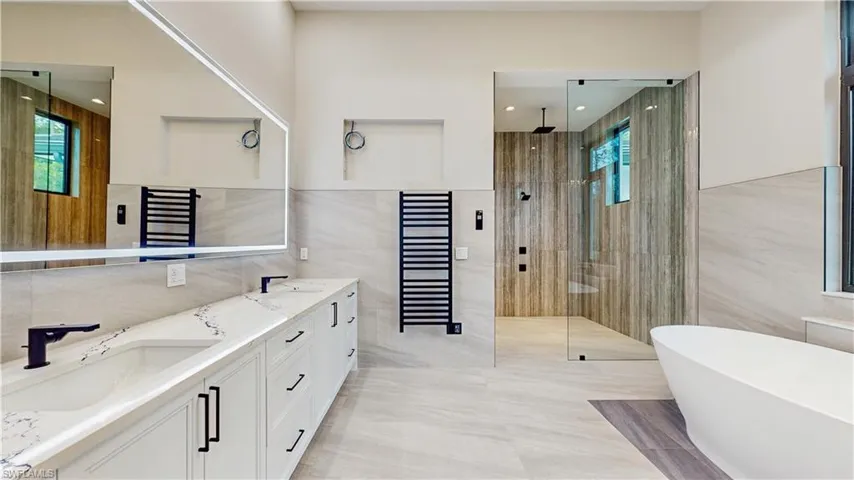 Bathroom featuring tile walls, vanity, and shower with separate bathtub