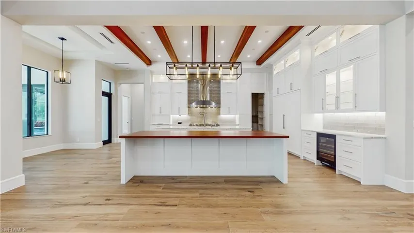 Kitchen featuring white cabinetry, wine cooler, decorative backsplash, and butcher block counters