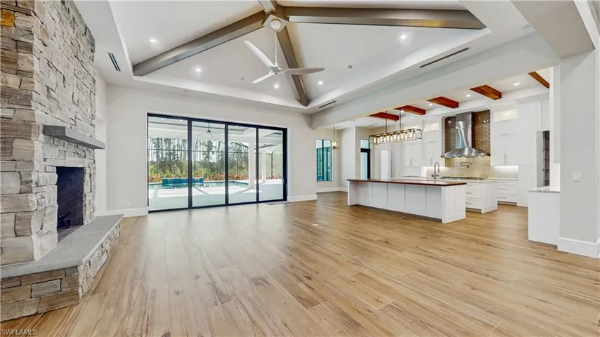 Unfurnished living room with light wood-type flooring, a towering ceiling, ceiling fan, a fireplace, and sink