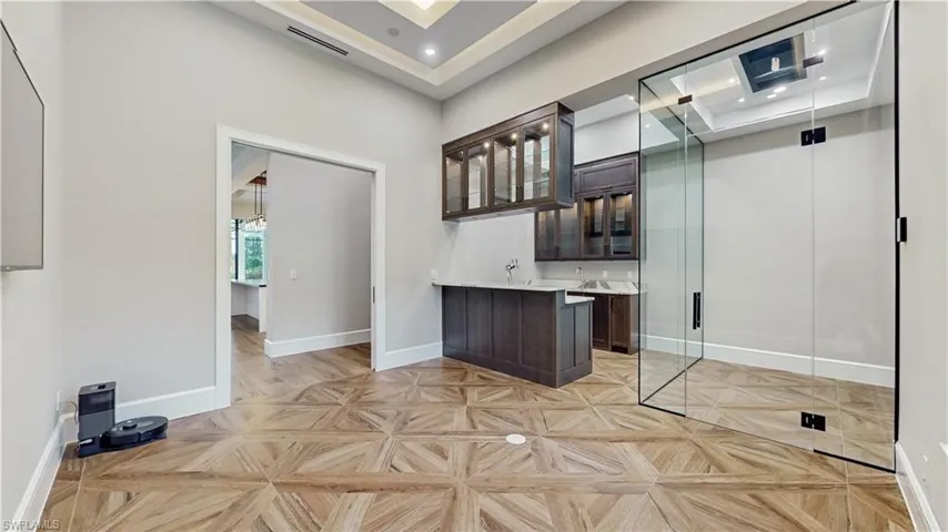 Bar with a towering ceiling, light parquet floors, and dark brown cabinetry