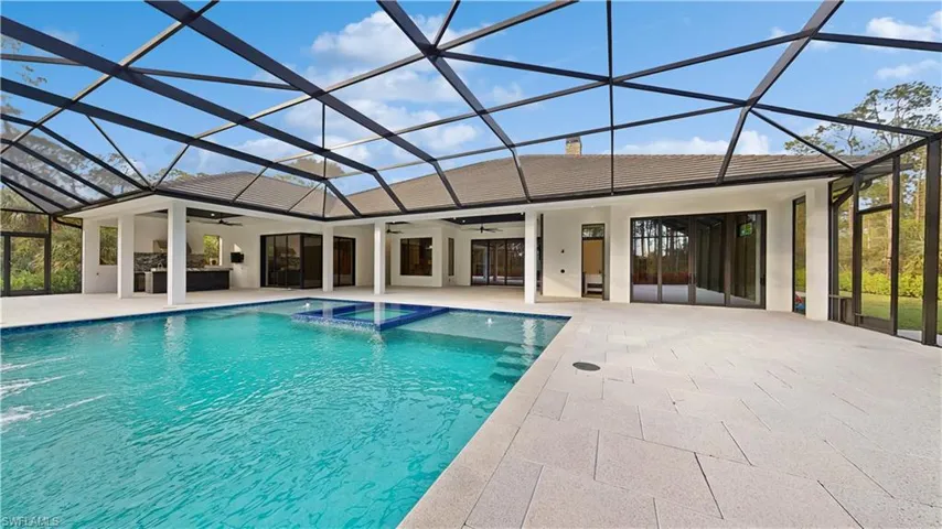 View of pool featuring ceiling fan, a patio, glass enclosure, and an in ground hot tub
