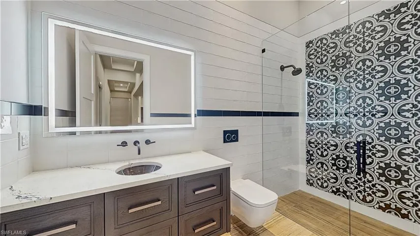Bathroom featuring toilet, a tile shower, decorative backsplash, tile walls, and vanity