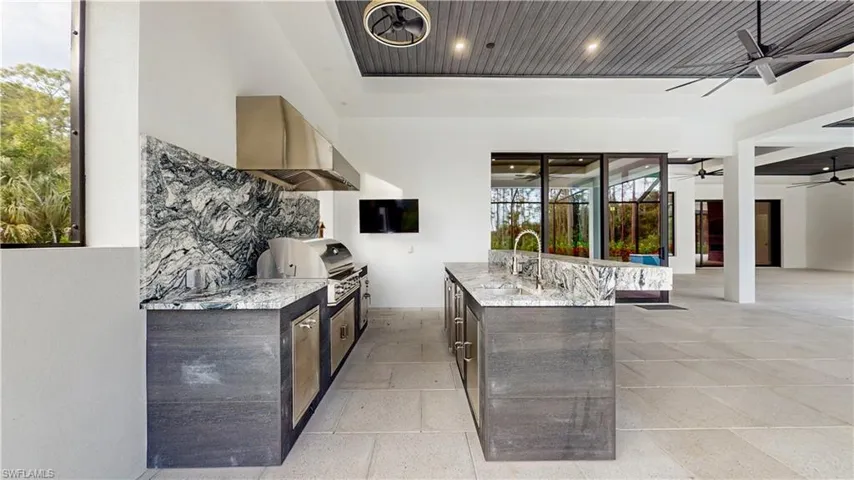 View of patio with an outdoor kitchen, sink, ceiling fan, and a grill