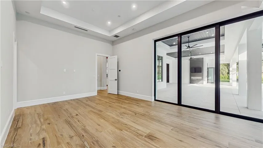 Unfurnished room featuring ceiling fan, a tray ceiling, and light hardwood / wood-style flooring