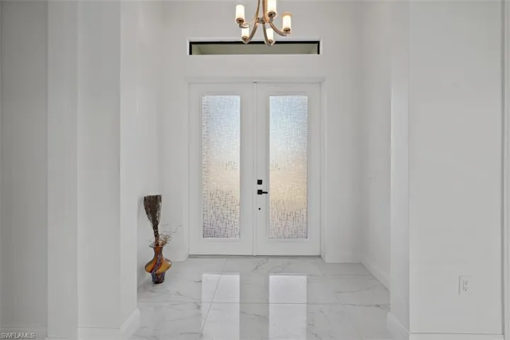 Entryway with french doors, marble finish flooring, and a chandelier