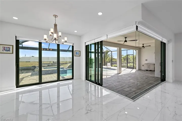Unfurnished dining area featuring light marble finish flooring, a sunroom, recessed lighting, and a chandelier