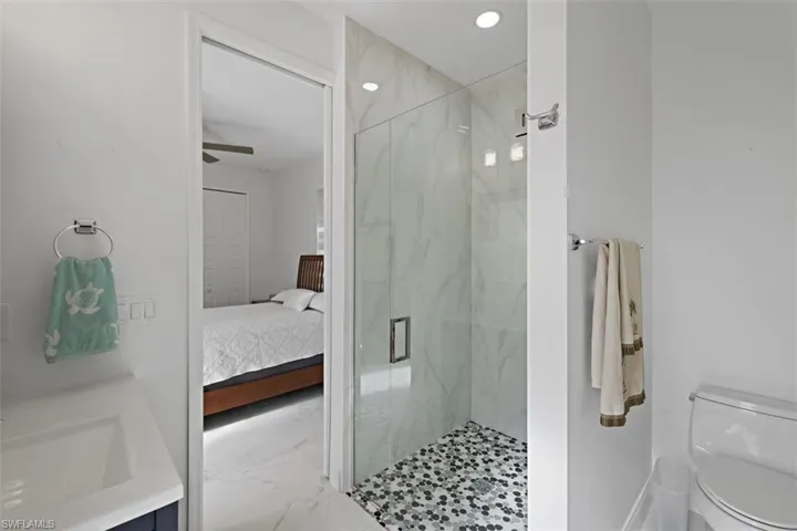 Ensuite bathroom with marble look tile flooring, vanity, a marble finish shower, recessed lighting, and a ceiling fan