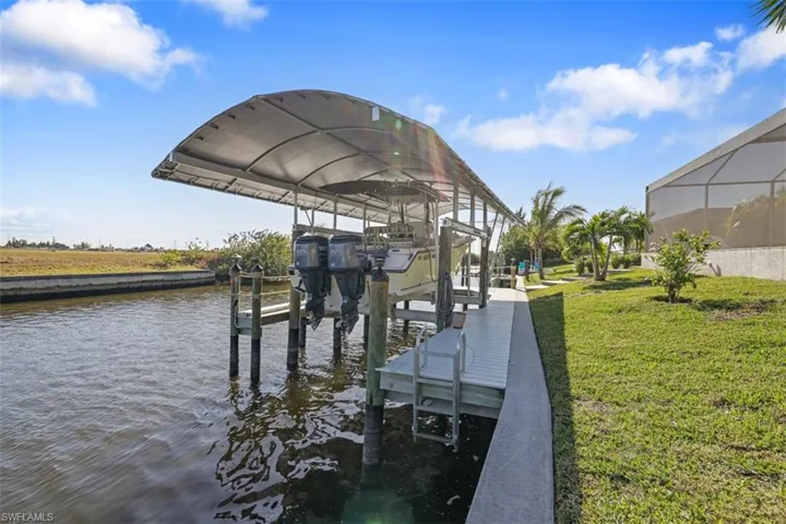 Dock featuring a lawn, a water view, boat lift, and a sunroom